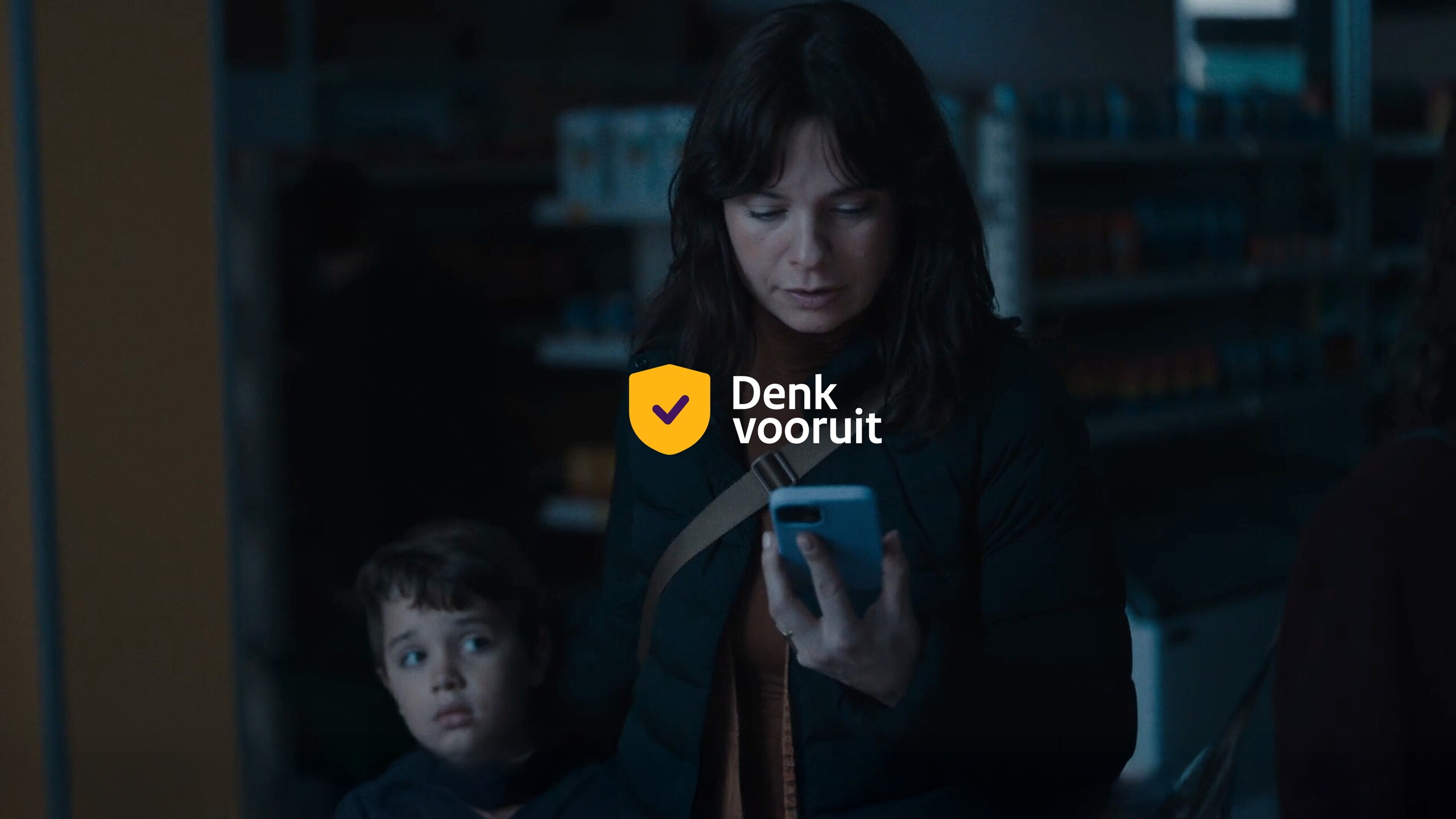Moeder en zoontje in winkel tijdens stroomuitval met het logo Denk vooruit